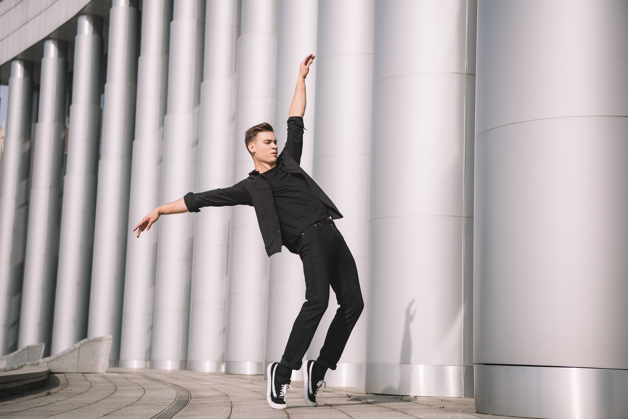 handsome young modern dancer dancing near columns